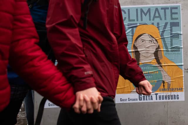 A couple walk past a poster advertising the presence of Swedish environmentalist Greta Thunberg during a Bristol Youth Strike 4 Climate (BYS4C) march, on February 28, 2020 in Bristol. 