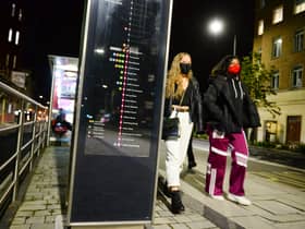 Two women wearing protective face masks walk past a bus stop in Bristol  (Photo by Finnbarr Webster/Getty Images)