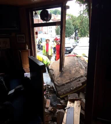 Firefighters assess the damage after a car hurtled into the front wall of the Merchant’s Arms.