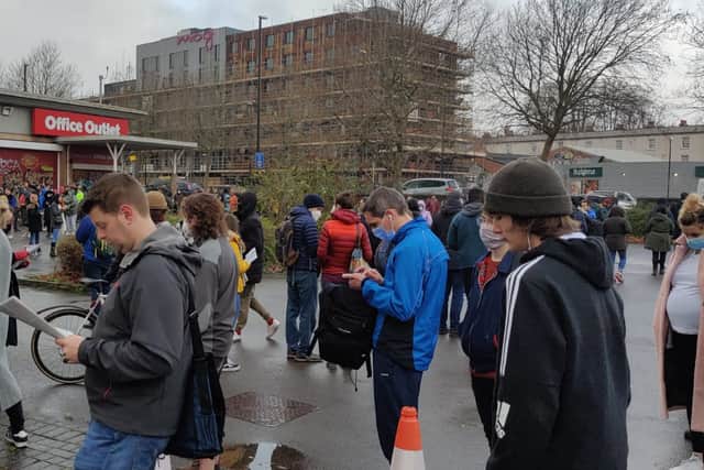 People keep themselves busy while waiting in the queue at Bristol Rapid Test Centre