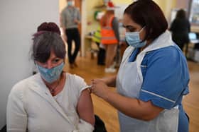 A woman receives a Covid vaccine as the UK steps up the country’s booster drive to fight a “tidal wave” of Omicron