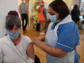 A woman receives a Covid vaccine as the UK steps up the country’s booster drive to fight a “tidal wave” of Omicron