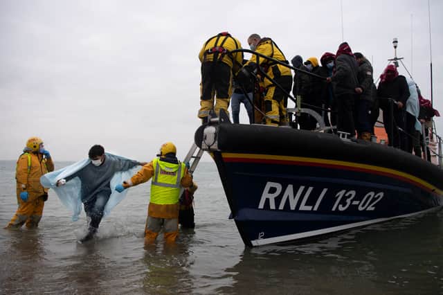 Migrants are helped ashore from a RNLI (Royal National Lifeboat Institution) lifeboat at a beach in Dungeness, on the south-east coast of England, on November 24, 2021, after being rescued while crossing the English Channel