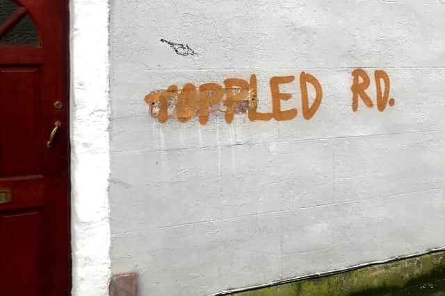‘Toppled Rd’ sprayed in graffiti opposite the new sign.