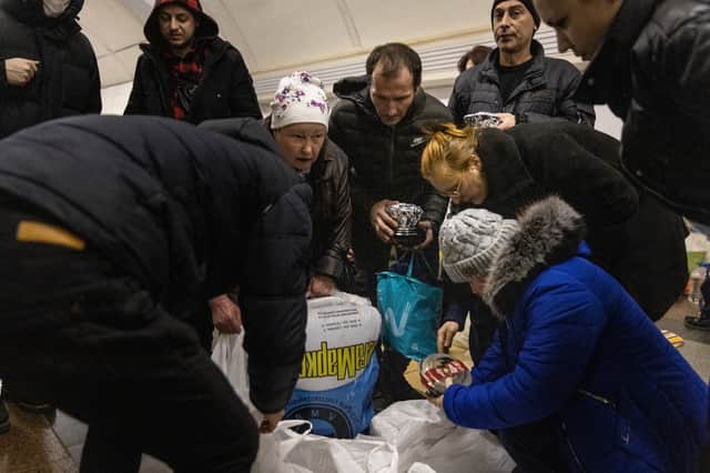 People pass out food that was delivered to people sheltering in the Dorohozhychi subway station in Kyivv which has has been turned into a bomb shelter