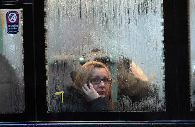 A woman looks out of the window of a bus as it waits at a bus stop in the rain in Bristol, England (Photo by Matt Cardy/Getty Images)