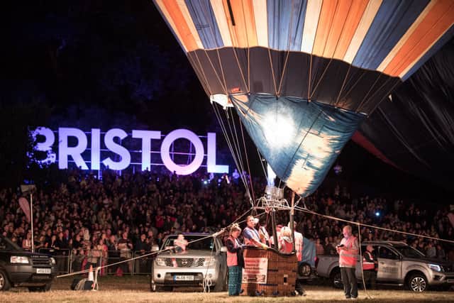 Crowds watch as tethered balloons are illuminated by their burners during the nightglow evening event at Ashton Court.
