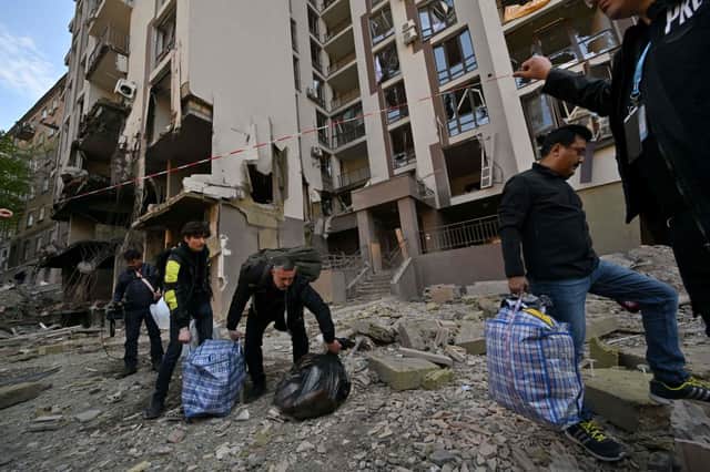 Residents carry their belongings as they leave their damaged building following Russian strikes in Kyiv on April 29.