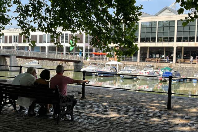 A group of people sit in the shade as the sun basks down on the harbourside in Bristol