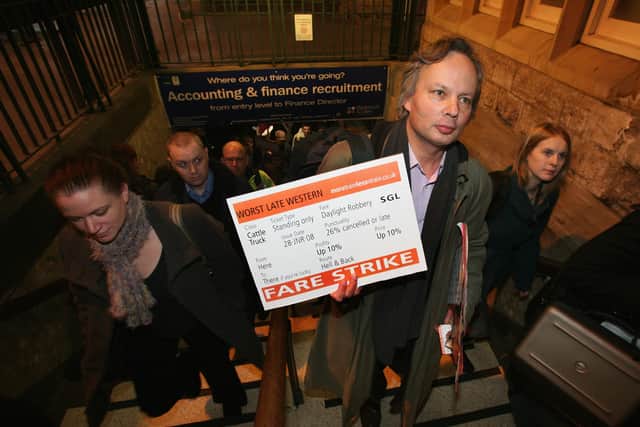   A commuter protester from Bristol-based passenger group, More Train Less Strain, holds a placard urging passengers to take a fare strike