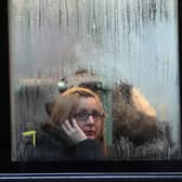 A woman looks out of the window of a bus as it waits at a bus stop in the rain in Bristol. 