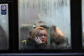 A woman looks out of the window of a bus as it waits at a bus stop in the rain in Bristol (Photo by Matt Cardy/Getty Images).