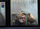 A woman looks out of the window of a bus as it waits at a bus stop in the rain in Bristol (Photo by Matt Cardy/Getty Images).