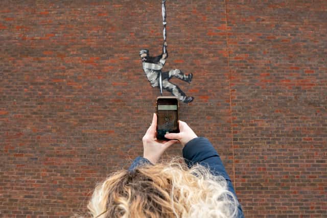 Members of the public take pictures of art work by graffiti artist Banksy on the side of HMP Reading depicting a prisoner escaping with a typewriter, an acknowledgement to one of the former prisoners Oscar Wilde.