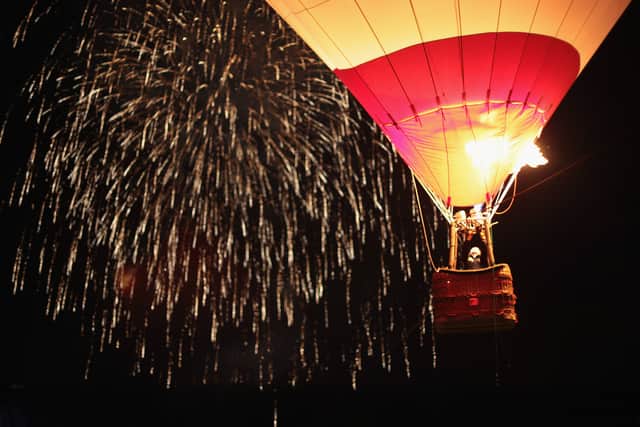 Crowds watch as tethered balloons are illuminated by their burners during the nightglow evening event at the Bristol International Balloon Fiesta (Photo by Matt Cardy/Getty Images).