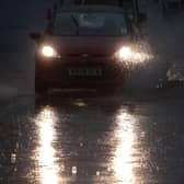  A motorist drives through a large pool of standing water as rain pours down along one of the main commuter routes into Bristol
