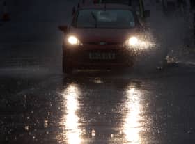  A motorist drives through a large pool of standing water as rain pours down along one of the main commuter routes into Bristol
