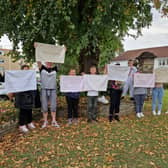 Parent and children hold banners at a protest outside Blaise High School