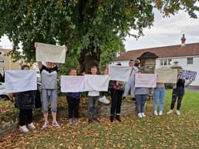Parent and children hold banners at a protest outside Blaise High School