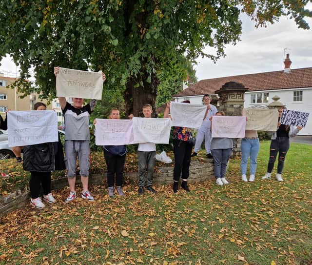 Parent and children hold banners at the protest outside Blaise High School