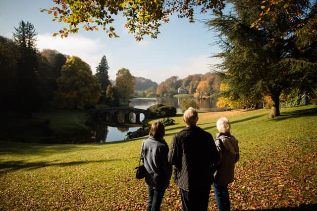 People gather to look at trees displaying their autumn colours surrounding the lake at the National Trust’s Stourhead in Wiltshire.