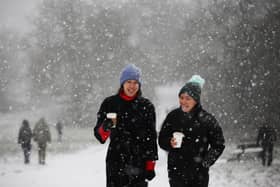 Two women walk as snow falls. (Photo by Hollie Adams/Getty Images)