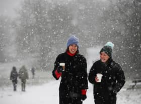 Two women walk as snow falls. (Photo by Hollie Adams/Getty Images)