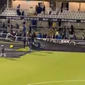 Bristol Rovers fans help with putting sheets on to the pitch immediately after the full-time whistle. 
