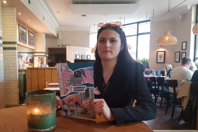 A member of Animal Rising protests at a table at the Cow & Sow in Queens Square