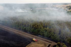 In this aerial view, a fire engine is seen on the field while smoke rises from the trees on July 19, 2022 in Blidworth, England
