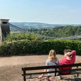 A couple take a break and enjoy the view over the Clifton Suspension Bridge from a seat outside Clifton Observatory.