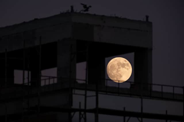 The waxing gibbous moon rises behind a building a day ahead of the July “buck supermoon”. 