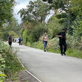 An armed police officer searches the hedgerow along the Bristol to Bath railway path on Friday