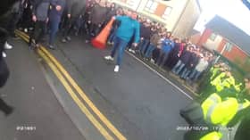Drunk football supporter wields traffic cone at wall of police.