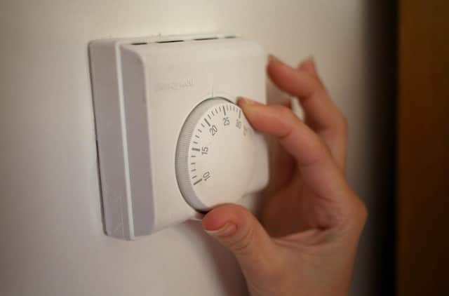 <p>Undated file photo of a person using a central heating thermostat.</p>
