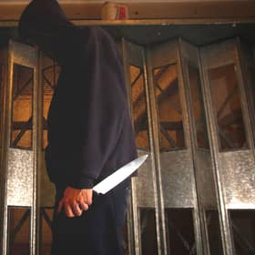 PICTURE POSED BY MODEL. A general view of a man in a hoodie holding a knife.