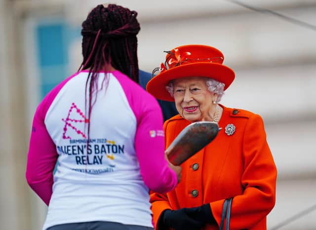 LONDON, ENGLAND - OCTOBER 07: Queen Elizabeth II passes her baton to the baton bearer, British parasport athlete Kadeena Cox, during the launch of the Queen's Baton Relay for Birmingham 2022, the XXII Commonwealth Games at Buckingham Palace on October 7, 2021 in London, England. The Queen and The Earl of Wessex are Patron and Vice-Patron of the Commonwealth Games Federation respectively. (Photo by Victoria Jones - WPA Pool/Getty Images)